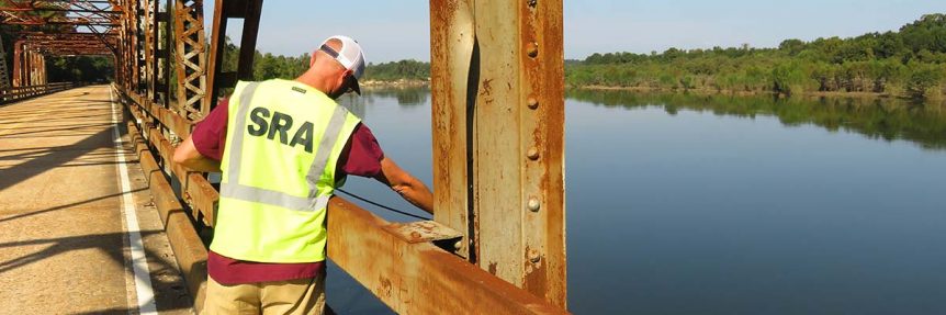 Man monitoring water quality from bridge