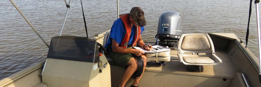 Man filling our report in boat on the water